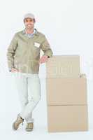 Confident delivery man standing by stack of boxes