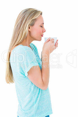 Pretty blonde standing and holding hot beverage