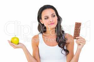 Pretty brunette deciding between apple and chocolate
