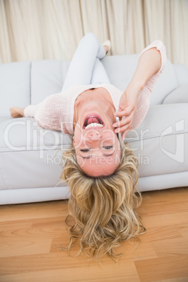 Pretty blonde lying on couch laughing on the phone