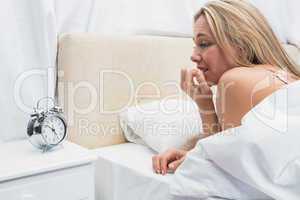 Anxious blonde looking her alarm clock