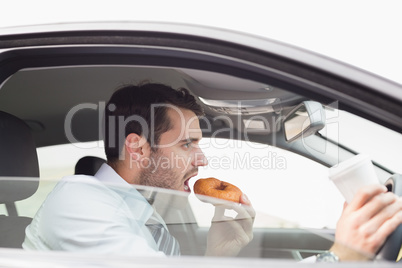 Young businessman having coffee and doughnut