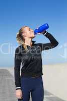 Fit blonde drinking water on the pier