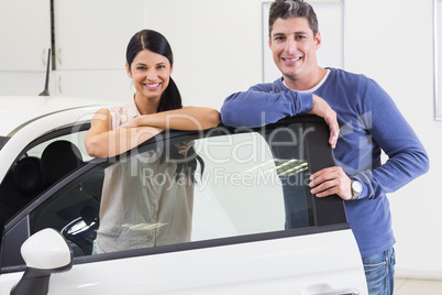 Smiling couple leaning on car