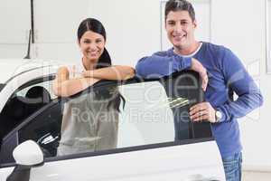 Smiling couple leaning on car