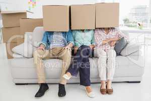 Colleagues sitting on couch covering with cardboard box