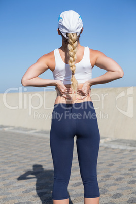 Fit blonde touching her back on the pier