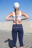 Fit blonde touching her back on the pier