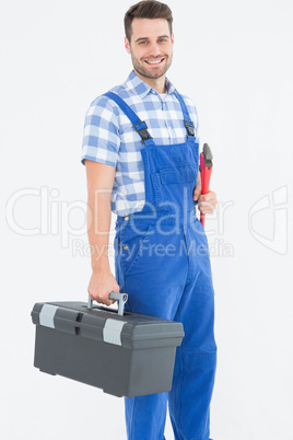 Smiling young male repairman carrying toolbox