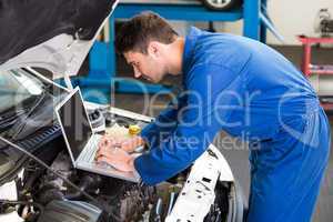 Mechanic using laptop on car