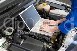 Mechanic using laptop on car