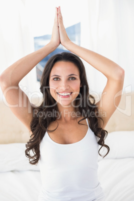 Calm brunette doing yoga on bed