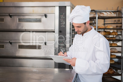 Focused baker writing on clipboard