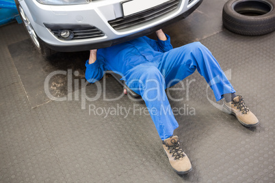 Mechanic lying and working under car