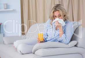 Blonde with glass of orange juice and sneezing