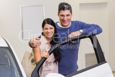 Smiling couple leaning on car