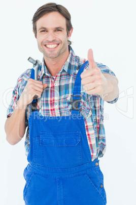 Confident plumber holding tool while gesturing thumbs up