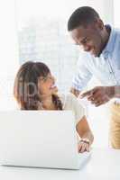 Happy coworkers using laptop together