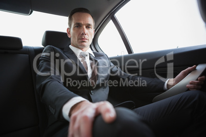 Unsmiling businessman sitting in the back seat