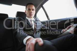 Unsmiling businessman sitting in the back seat