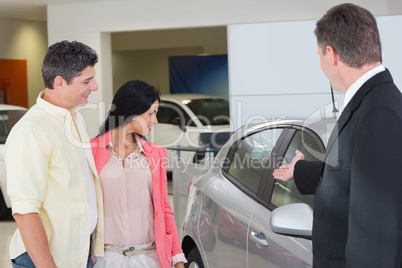 Businessman showing a car to a couple Businessman showing a car to a couple