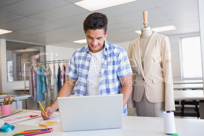 Cheerful student drawing picture while using laptop