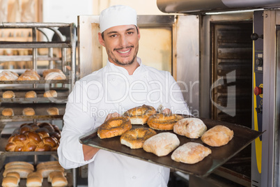 Happy baker showing tray of fresh bread