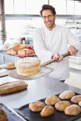 Baker showing freshly baked loaf