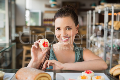 Pretty brunette showing a cupcake