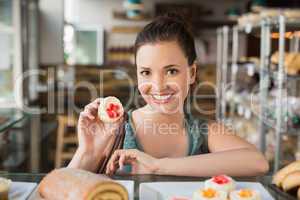 Pretty brunette showing a cupcake