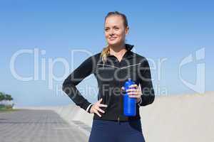 Fit blonde holding bottle on the pier