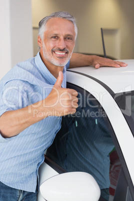 Smiling man hugging a white car while giving thumbs up Smiling man hugging a white car while giving thumbs up