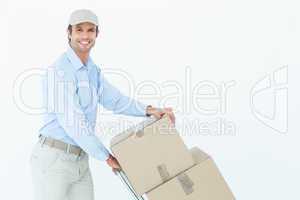 Confident delivery man pushing trolley of cardboard boxes