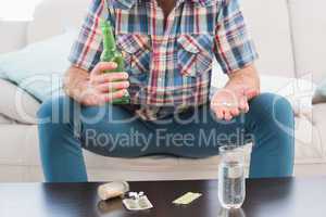 Man with a beer and his medicine laid