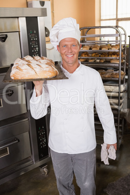 Baker holding tray of bread