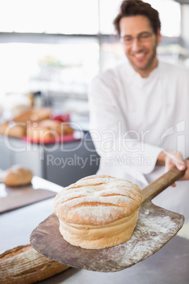 Baker showing freshly baked loaf