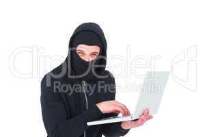 Hacker in balaclava using laptop to steal identity