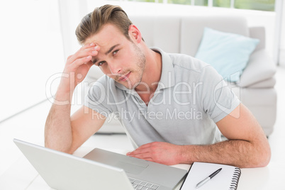 Anxious businessman using laptop and notebook