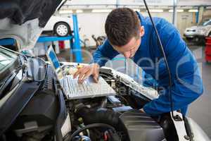 Mechanic using laptop on car