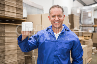 Smiling warehouse worker holding small box