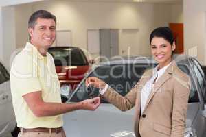 Smiling businesswoman giving car key to happy customer
