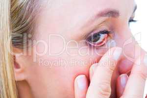 Close up of blonde applying contact lens