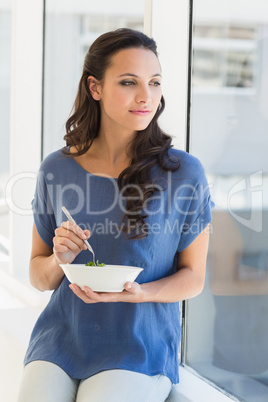 Pretty brunette eating a salad