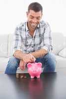 A man putting a pennie in a piggy bank