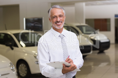 Smiling businessman writing on clipboard