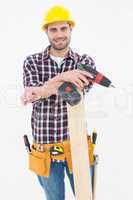 Confident male carpenter with drill machine and plank