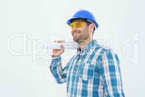 Smiling architect looking away while holding blueprint