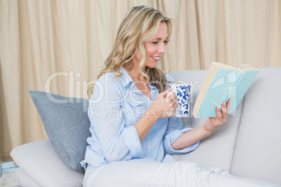 Smiling blonde reading a book with coffee