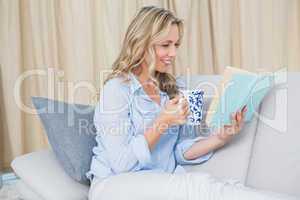 Smiling blonde reading a book with coffee