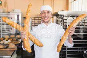 Smiling baker holding three baguettes